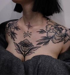 a woman's chest with flowers and stars tattooed on her upper part, in black ink