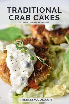 two crab cakes with white sauce on top of lettuce and garnish