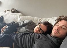 a man and woman laying on top of a couch next to each other with their eyes closed