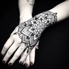 a woman's hand with black and white henna tattoos on her left arm