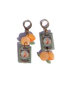 two oranges are hanging from the back of some keychains on a white background