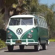 a green and white vw bus parked on the side of the road with palm trees in the background