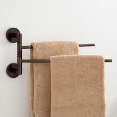 two towels are hanging on the wall next to each other, one is brown and the other is beige