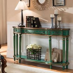 a green console table with two lamps and pictures on the wall