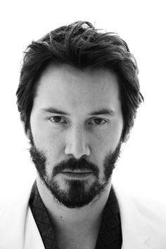 a black and white photo of a man with a beard wearing a suit shirt and tie