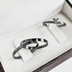 two silver rings sitting in a white box