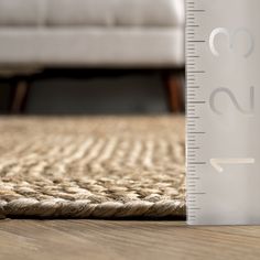 a ruler is on the floor next to a couch and rug with a white sofa in the background