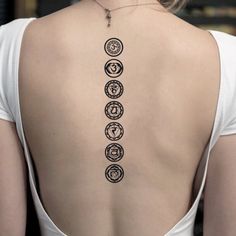 the back of a woman's neck with seven chakragrams on it