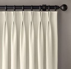 white curtains hanging on the side of a window with black metal rods and an iron rod