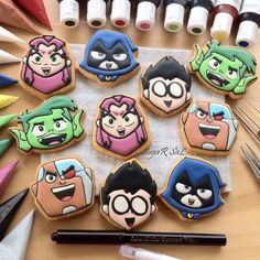 decorated cookies with cartoon characters are on a table next to markers, pens and markers