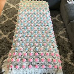 a crocheted blanket sitting on top of a carpet next to a couch and chair