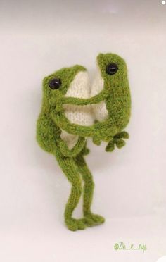 a knitted frog holding onto the back of its head