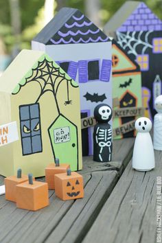 halloween paper houses are sitting on a table with ghost figurines and pumpkins