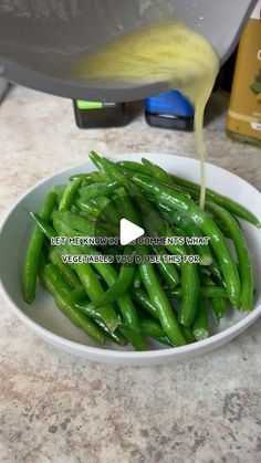 green beans in a white bowl being drizzled with mustard