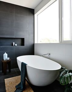 a white bath tub sitting in a bathroom next to a window with potted plants