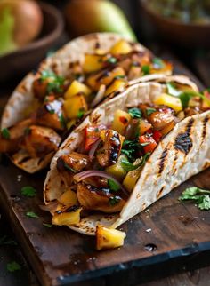 two tacos with pineapples, onions and cilantro on a cutting board