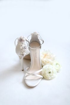 a pair of white high heel shoes next to flowers