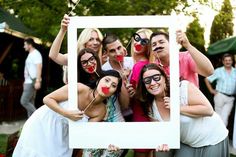 a group of people posing for the camera with their faces painted like clowns holding up a photo frame