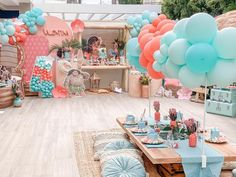 a room filled with lots of balloons and tables covered in blue, orange and pink decorations