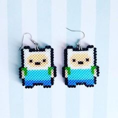 a pair of earrings made to look like pixelo from adventure time on a blue and white striped background