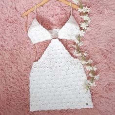 white crochet halter top and skirt with flowers on hanger next to pink carpet