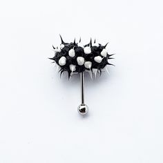 a black and white pin with spikes on it's end is shown in front of a white background