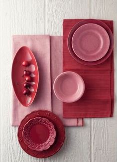 a table setting with plates, bowls and cups on top of pink placemats