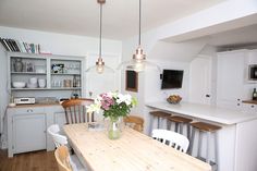 a kitchen with white cabinets and wooden table surrounded by chairs in front of an island