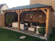 a wooden gazebo sitting on top of a grass covered yard next to a building