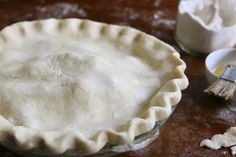 an uncooked pie crust sitting on top of a table next to other ingredients