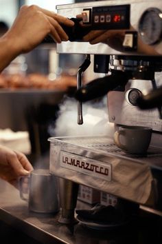 a person is using a coffee machine with steam coming out of it