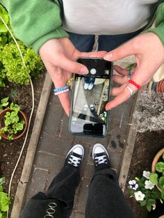 someone taking a selfie with their cell phone in front of some potted plants