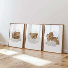 three framed teddy bears sitting on top of clouds in front of a white wall and wooden floor