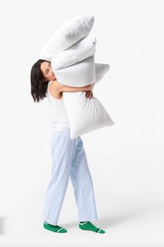 a woman carrying pillows while standing next to a pillow