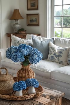 blue hydrangeas in a wicker vase on a coffee table next to a white couch