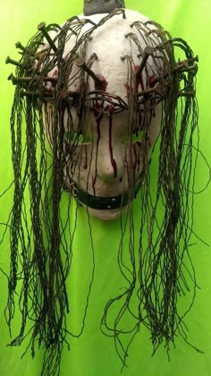 a creepy mask with vines on it's head is shown in front of a green background