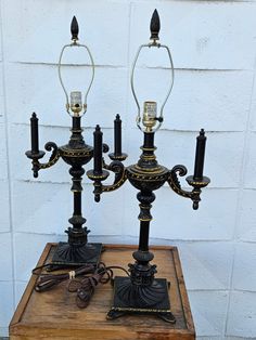 two black and gold candelabra lights sitting on top of a wooden table