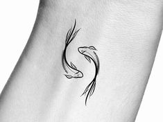 a small black and white koi fish tattoo on the back of a woman's neck