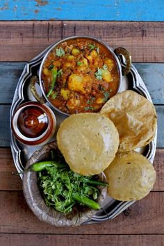 an overhead view of some food on a metal platter with chips and sauces