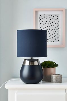 a blue lamp sitting on top of a white table next to a potted plant