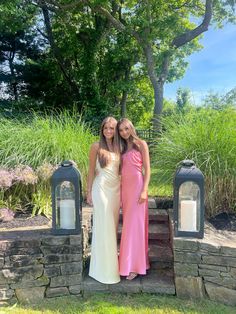 two women standing next to each other in front of some mailboxes and grass