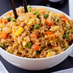 a white bowl filled with rice and veggies on top of a black table