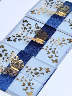 three pieces of blue and gold paper with butterflies on them