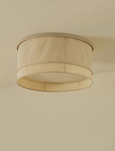 a white ceiling light hanging from the ceiling in a room with beige walls and flooring