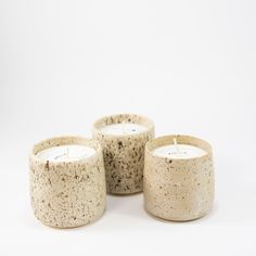 three candles sitting next to each other on a white surface with one candle lit in the middle