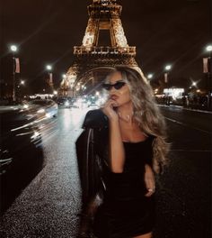 a woman is standing in front of the eiffel tower with her hand on her face