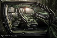 the interior of a green car with black trims and leather seats in front of trees