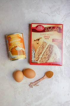 eggs, butter, and other ingredients for cake sitting on a white surface next to a can of doughnuts