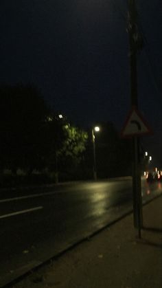 a street sign sitting on the side of a road at night