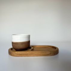 a white and brown cup sitting on top of a wooden tray